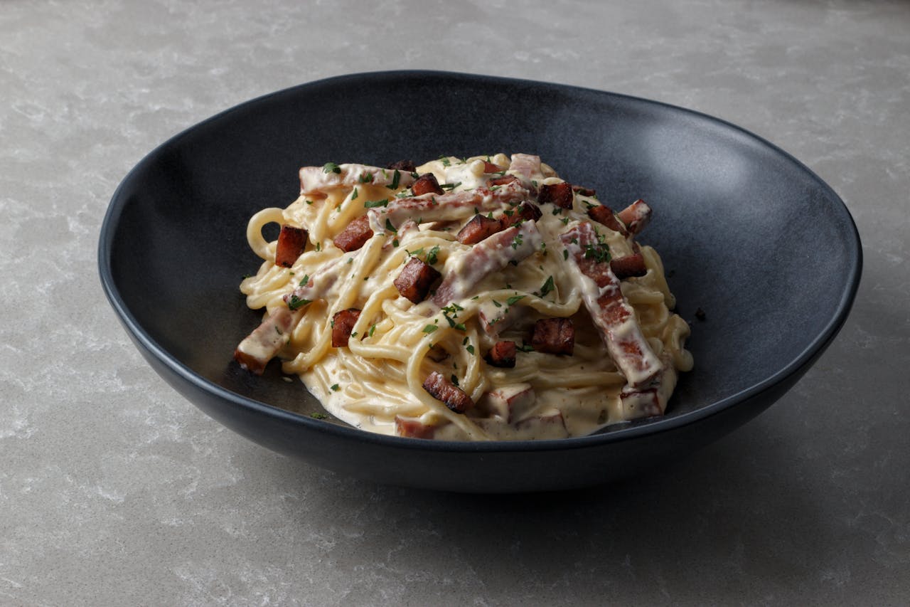Mouth-watering spaghetti carbonara with creamy sauce and crispy bacon bits served in a bowl.